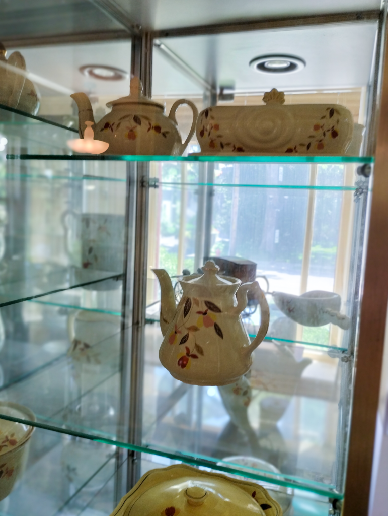 Photograph of a glass case filled with Jewel's Autumn Leaf teapots.