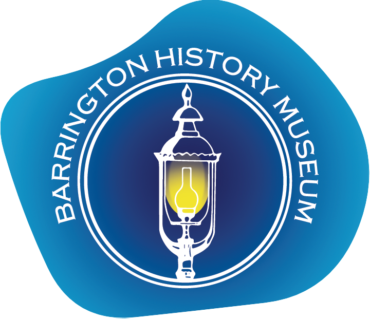 Logo image. The background is an irregular shape with a light to dark blue radial gradient. In the center of a white circle is a white line drawing of an old-fashioned gas streetlight with a glowing yellow center. White text over the circle says Barrington History Museum.